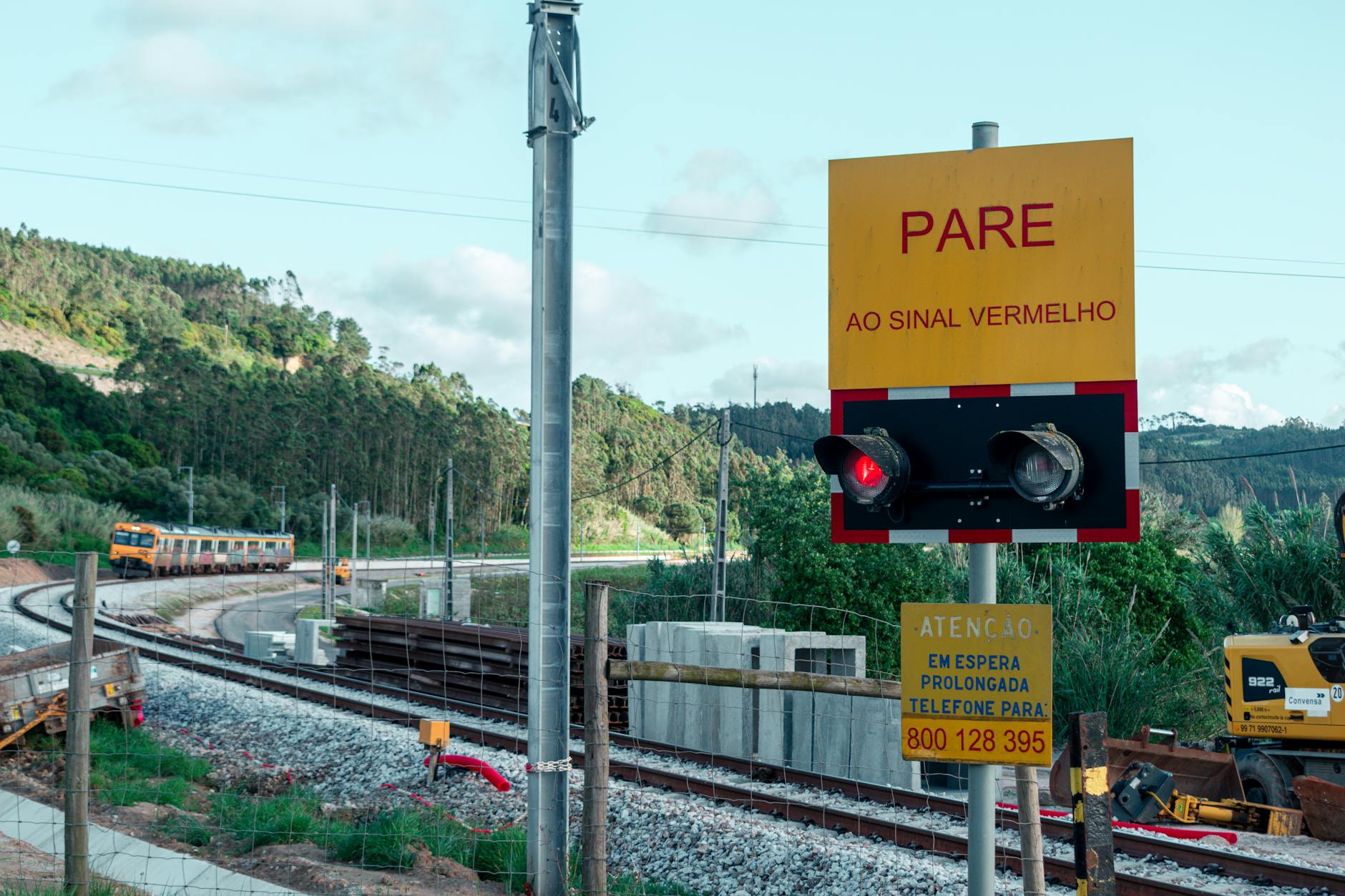 Nadjeżdżający pociąg przy przejeździe kolejowym ze znakiem stop PARE