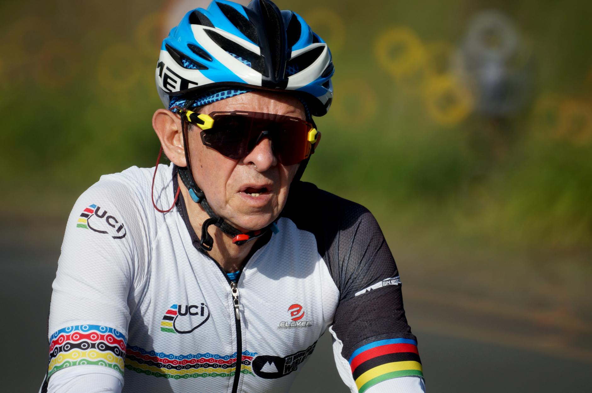 Starszy kolarz w kasku i okularach jedzie w wyścigu szosowym